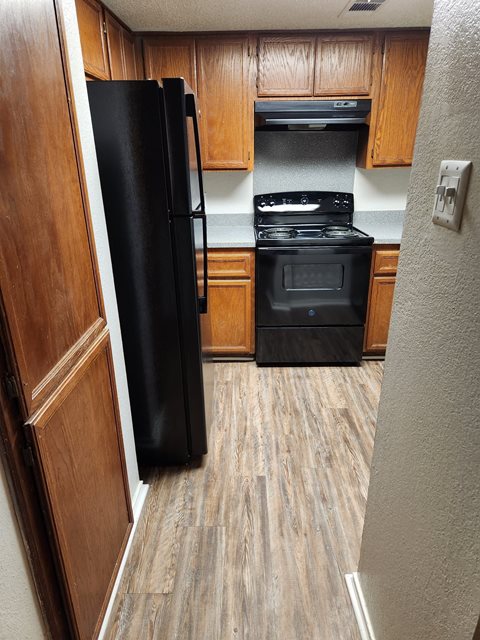 a kitchen with wood cabinets and a black stove and refrigerator
